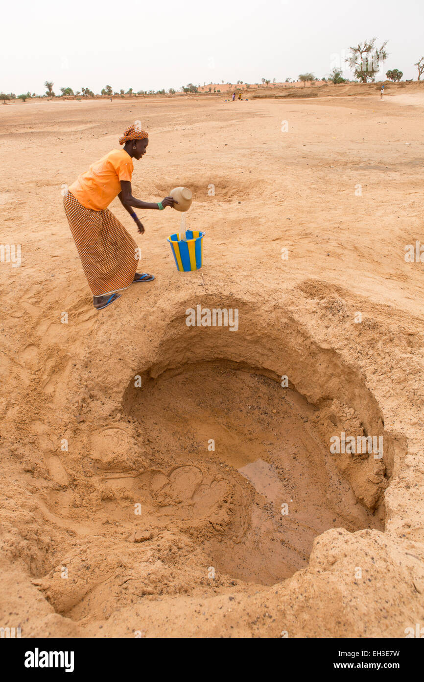 Western Niger, near Tera, 15th May 2012: Mariama Maiga, 14, collects water from a hand dug well in a dry river bed Stock Photo