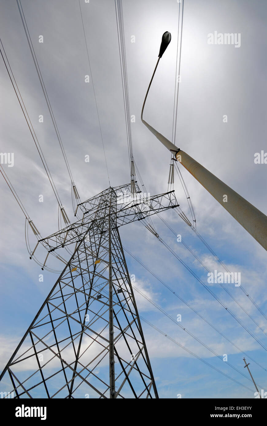 High voltage power supply lines and steel pylon next to street light ...