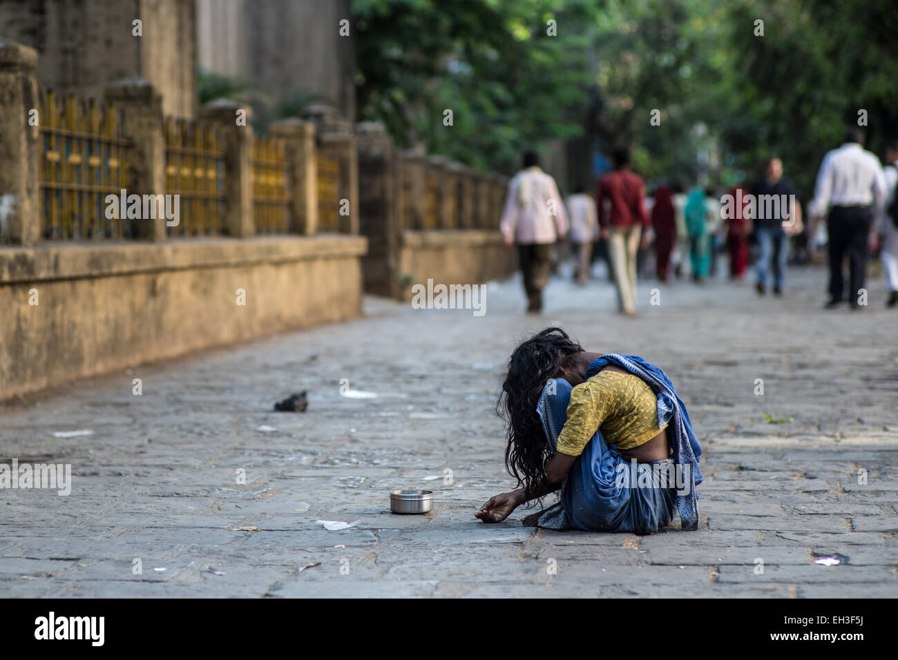 A young girl hiding her face while sitting and begging on the streets of Mumbai, India. Stock Photo
