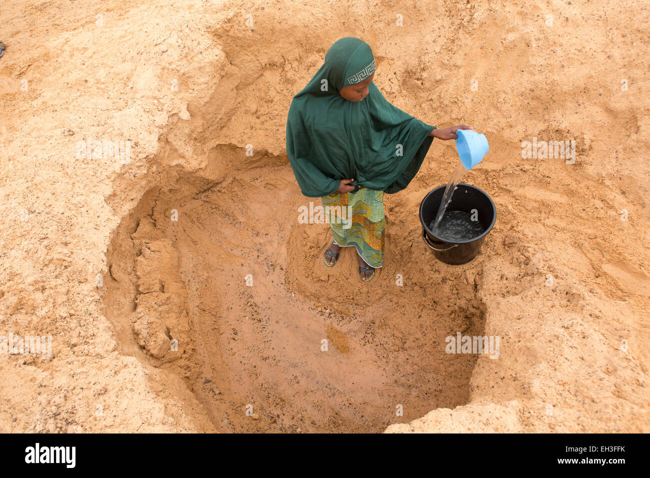 Western Niger, near Tera, 15th May 2012: Saffia Marou, 13, collects water from a hand dug well in a dry river bed. Stock Photo