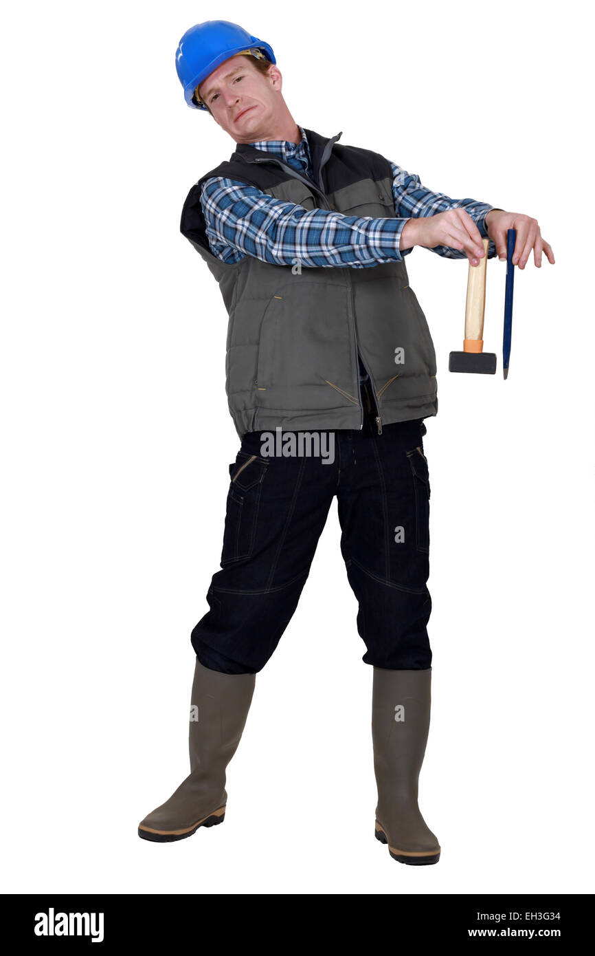 craftsman holding a hammer and a wedge and looking disgusted Stock Photo