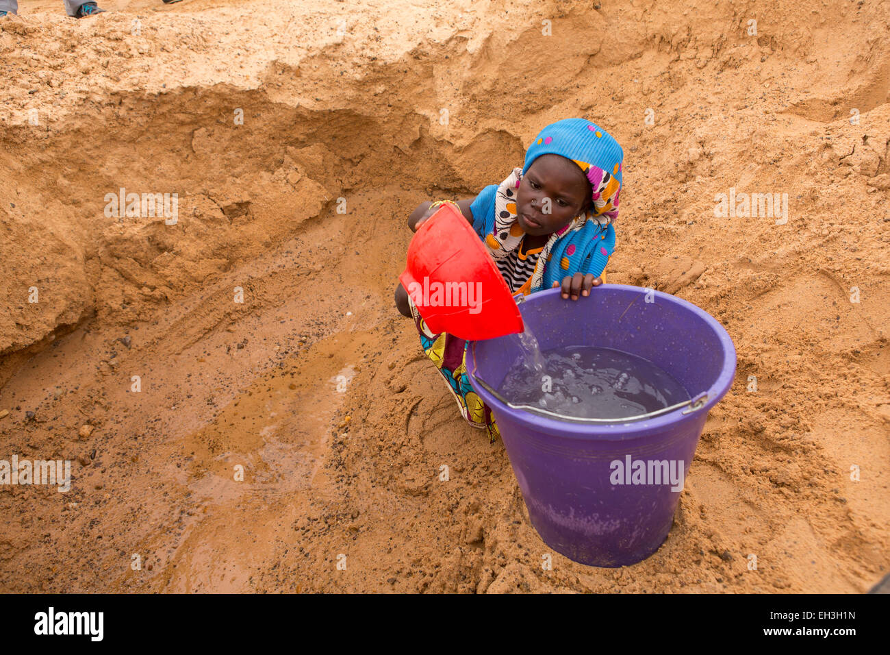 Western Niger, near Tera, 15th May 2012: Leyla Seydou, 11, collects water from a hand dug well in a dry river bed as there is insufficient supply of water in Kakassi village. Stock Photo