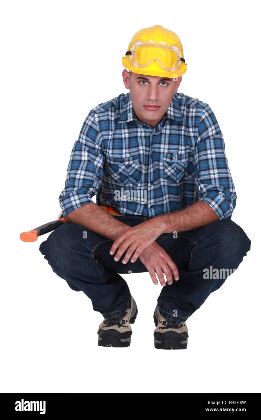 Squatting tradesman with a piercing stare Stock Photo