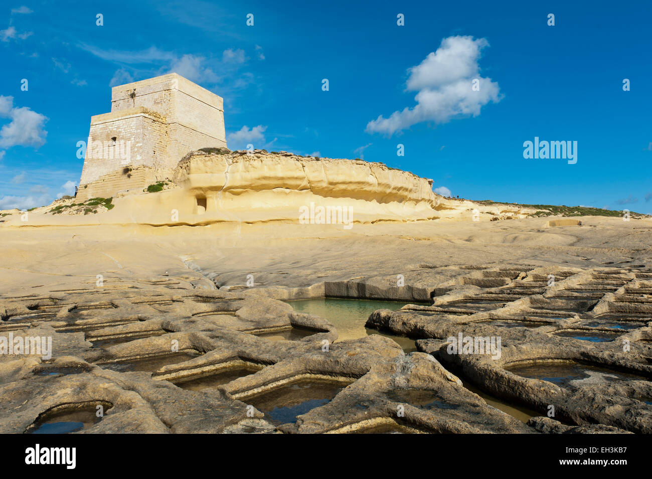 Xlendi Tower, coastal watchtower on a yellow sandstone cliff, sea salt extraction in salt pans