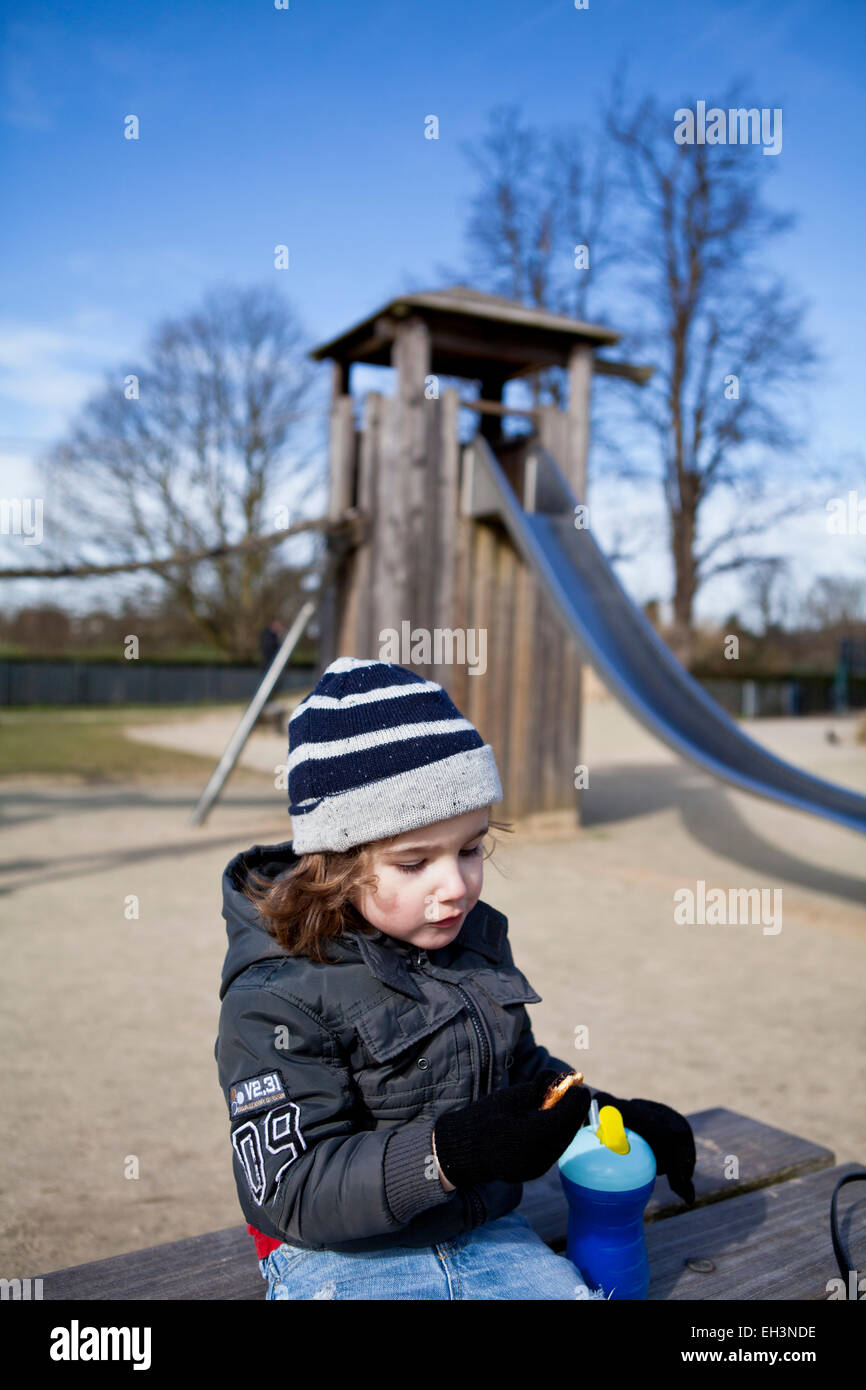 Toddler eating in a playground Stock Photo Alamy