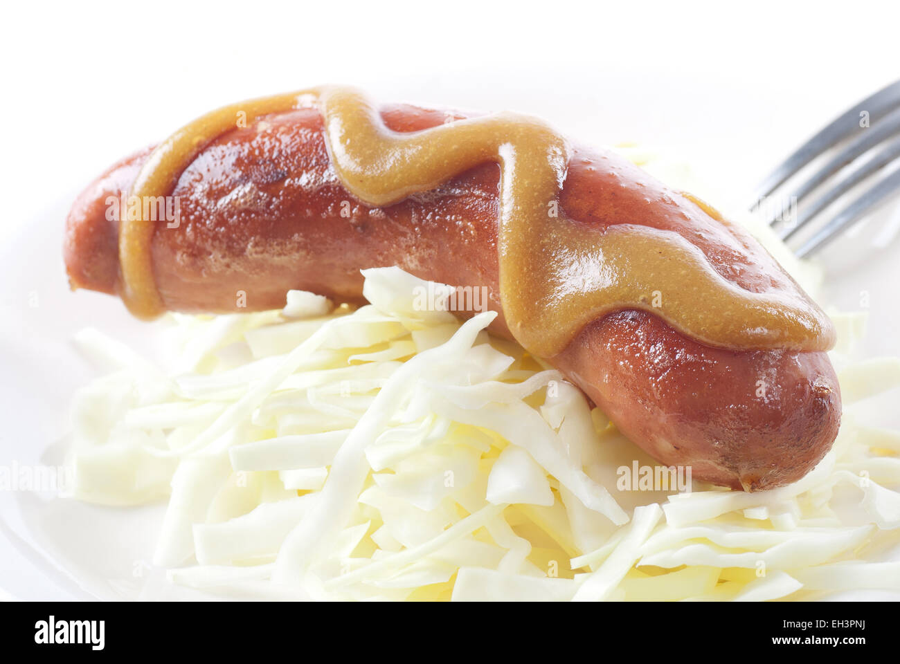 Grilled bratwurst with strong mustard on cabbage. Stock Photo