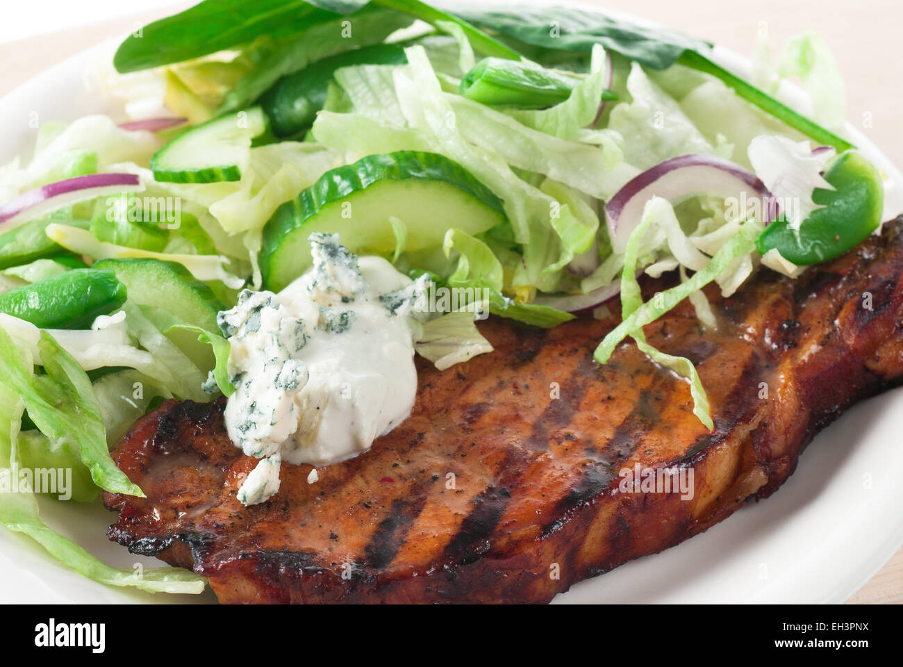 Grilled pork chop with blue cheese dressing and green salad. Stock Photo