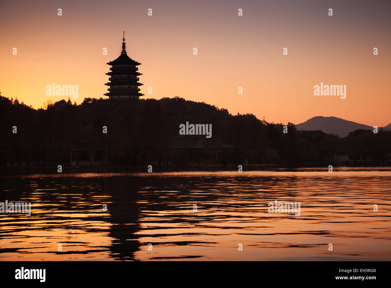 Black silhouette of traditional Chinese pagoda on orange evening sky background. Coast of West Lake. Famous park in Hangzhou cit Stock Photo
