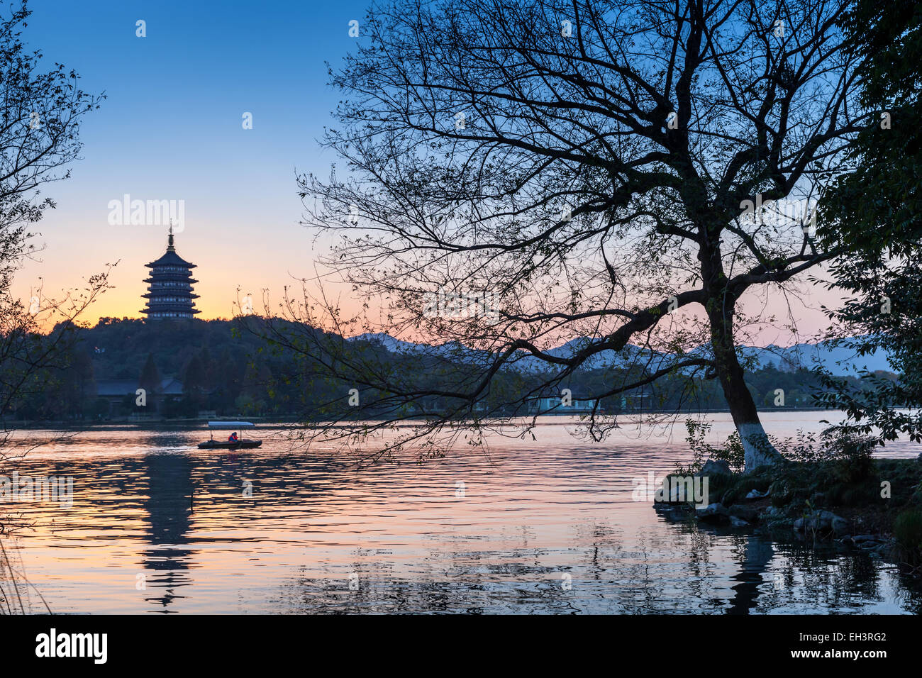 Black trees silhouette and traditional Chinese pagoda on the coast of West Lake. Famous park in Hangzhou city center, China Stock Photo