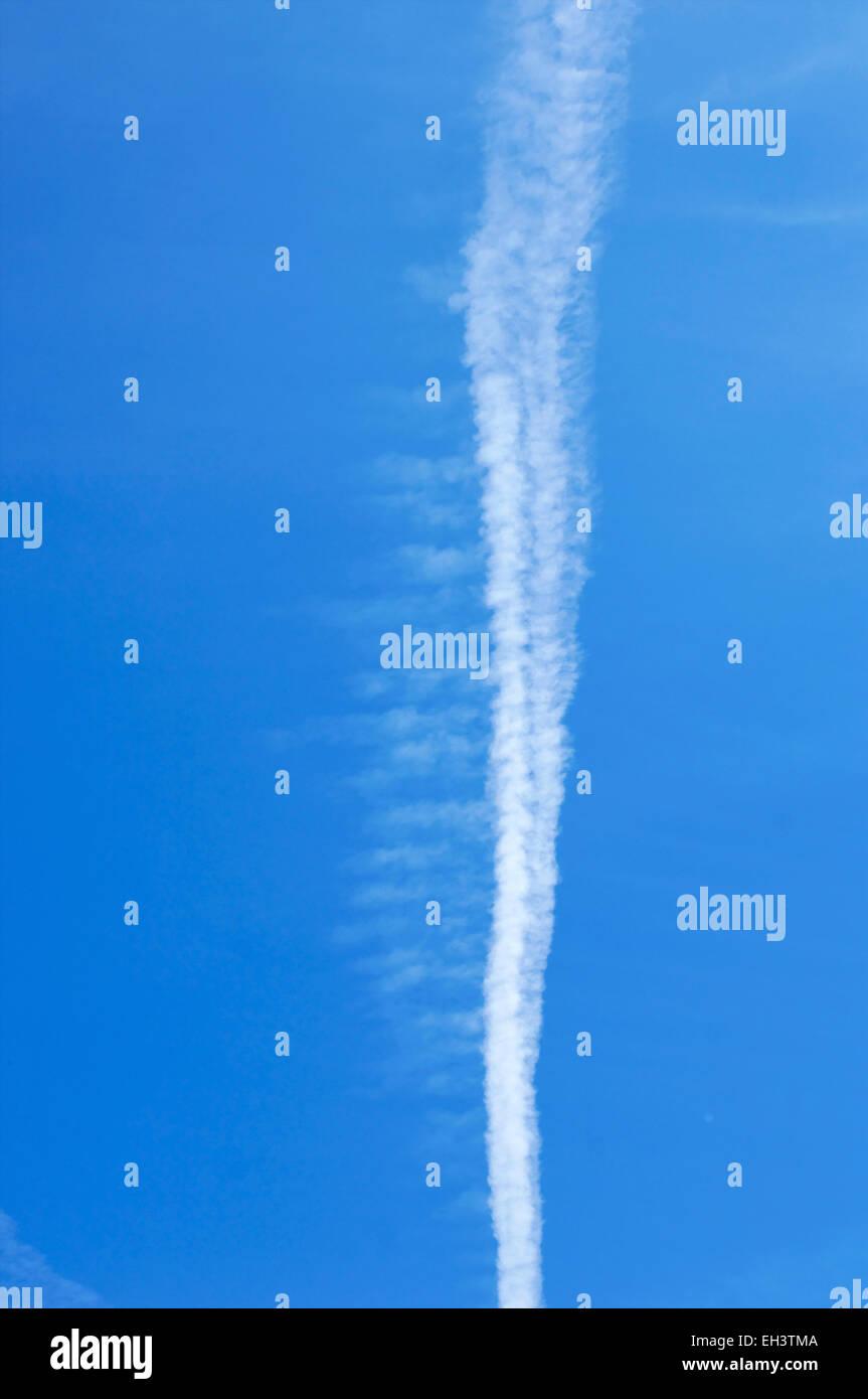 Blue sky with chemtrails left by airplanes in the air covering a blue sky  with artificial clouds containing toxic metals and chemicals Stock Photo