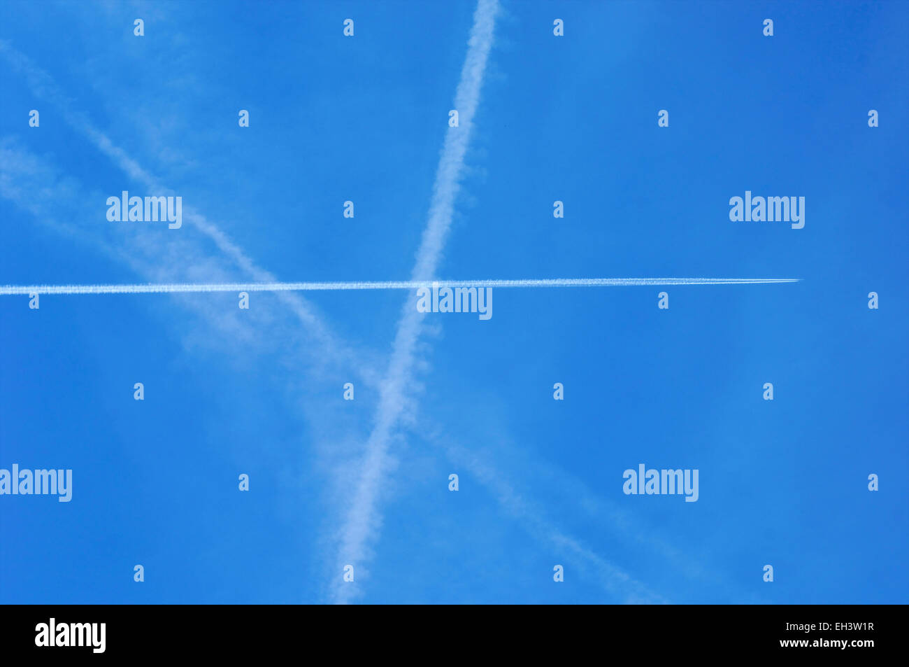 Blue sky with chemtrails or contrails in the air on a sunny day Stock Photo