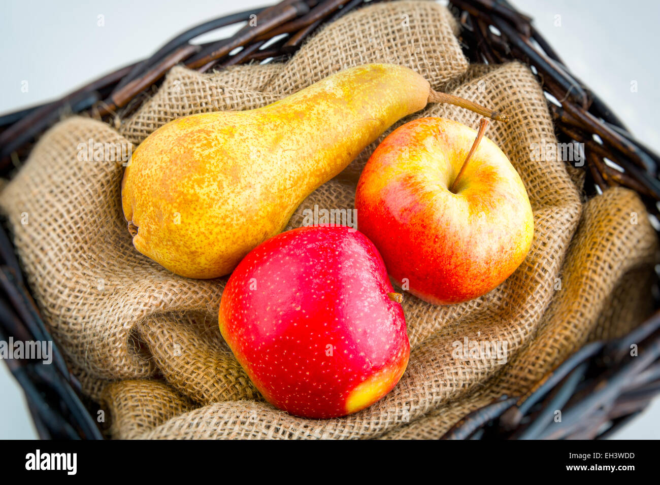 Two apples and pear in a wicker basket Stock Photo