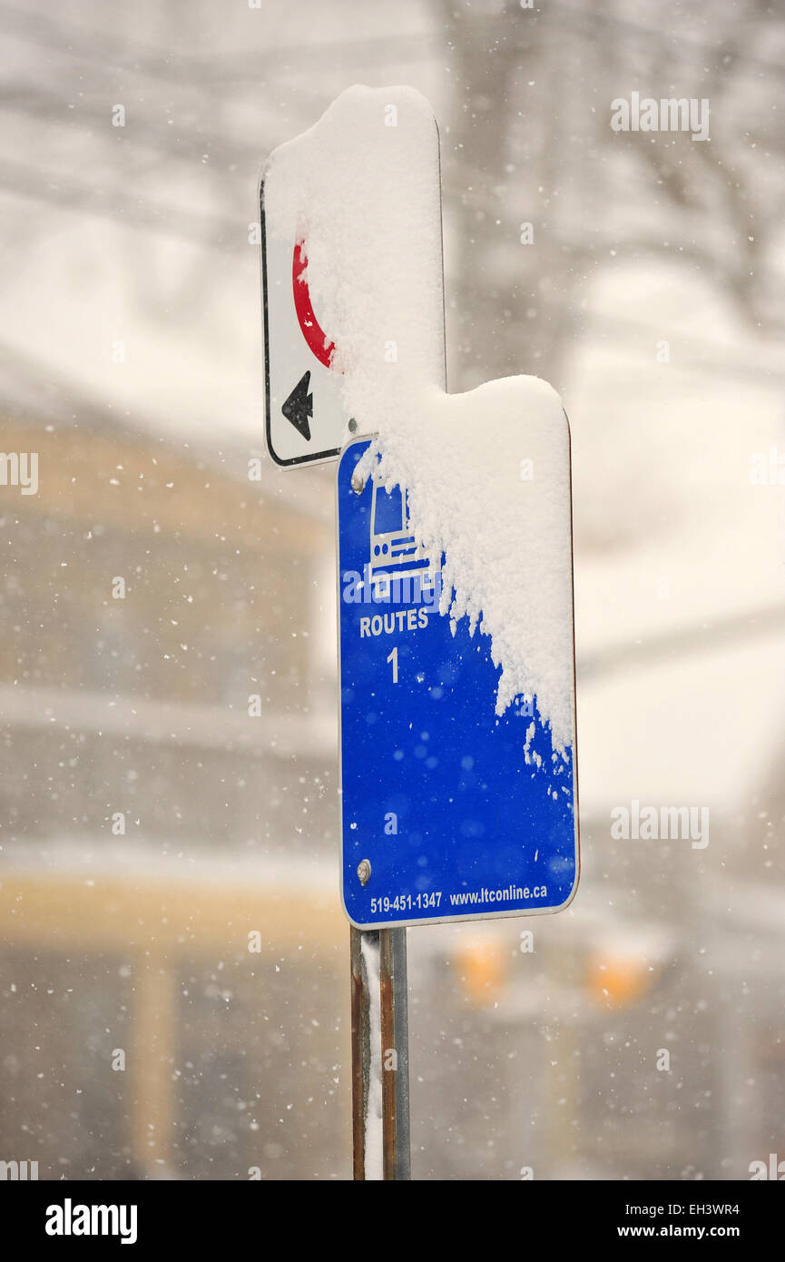 A Canadian bus stop sign half covered in a layer of snow. Stock Photo