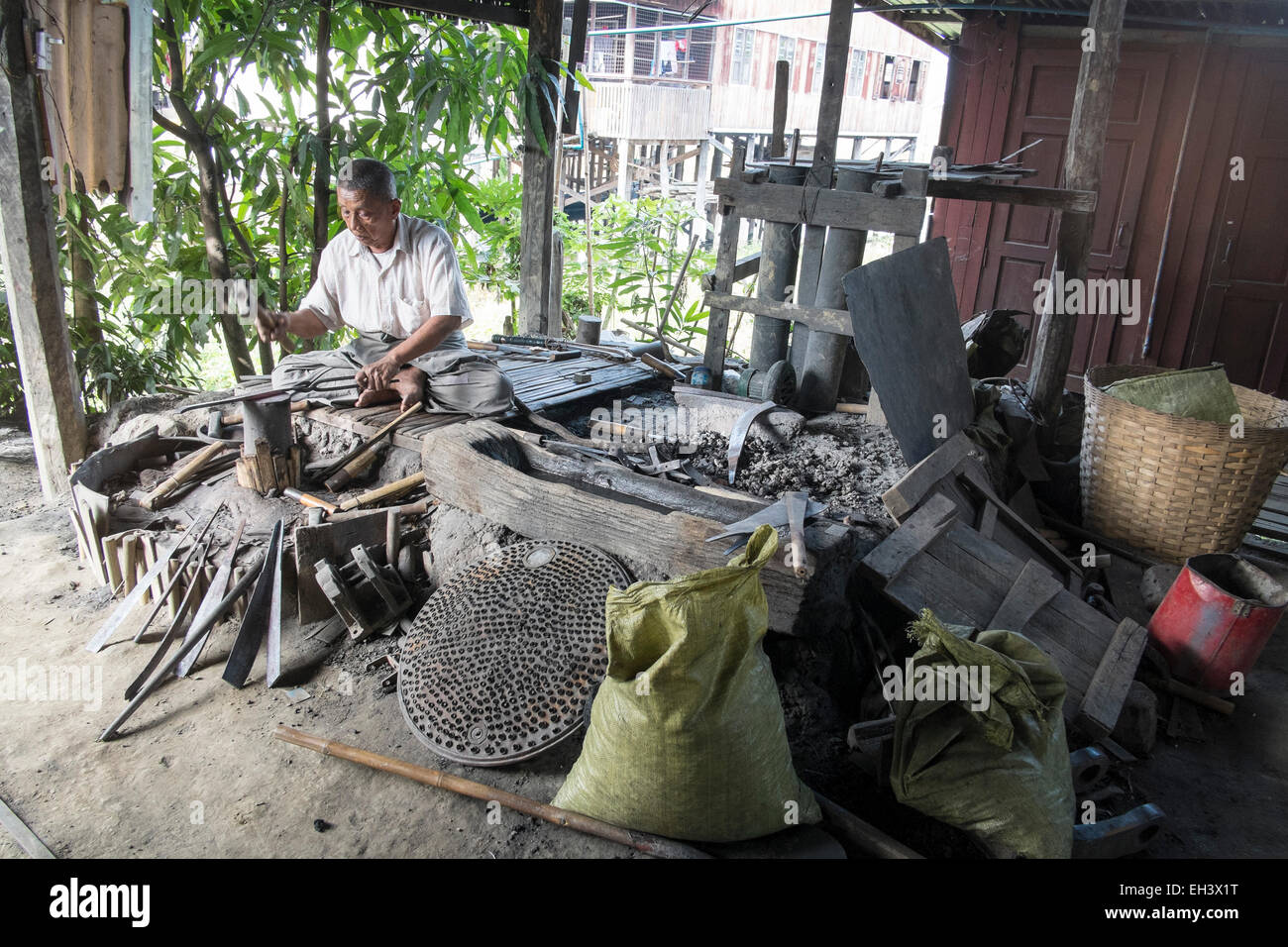 A metal worker works in a hut next to Inle Lake , Myanmar Stock Photo