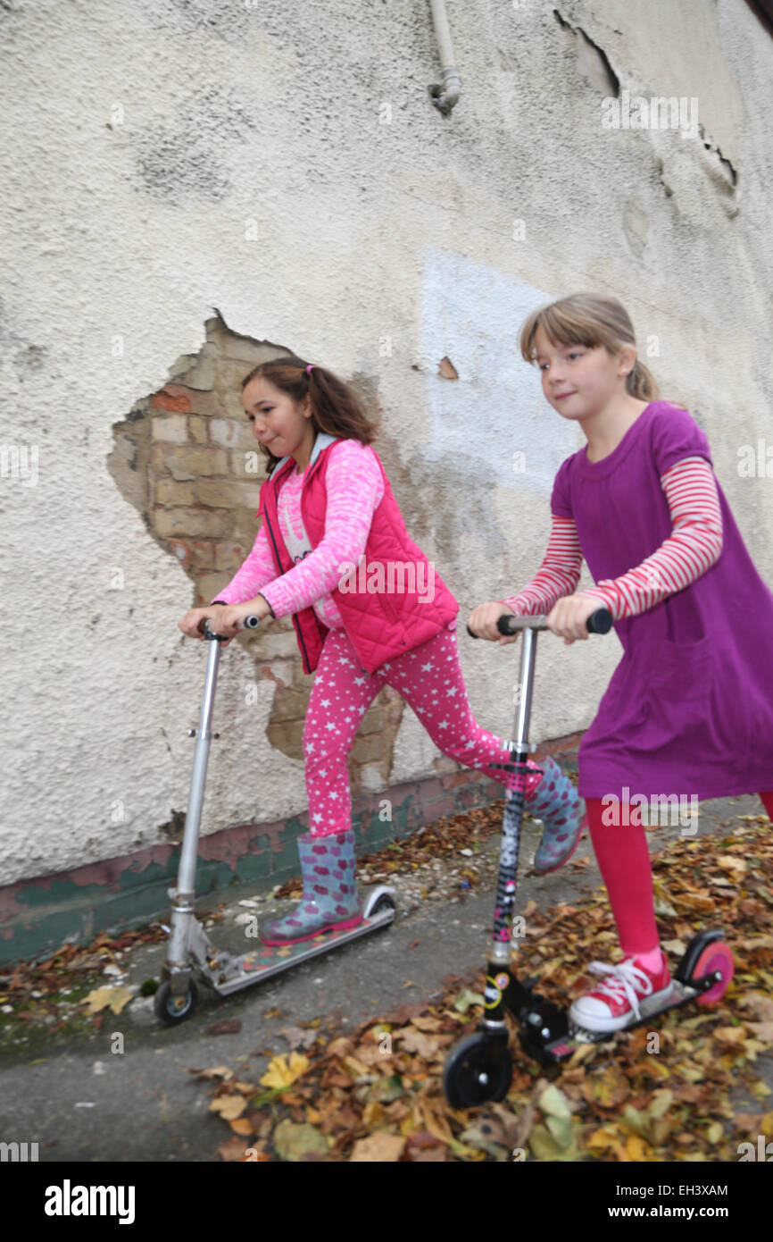 Girls playing on scooters in street - model released Stock Photo