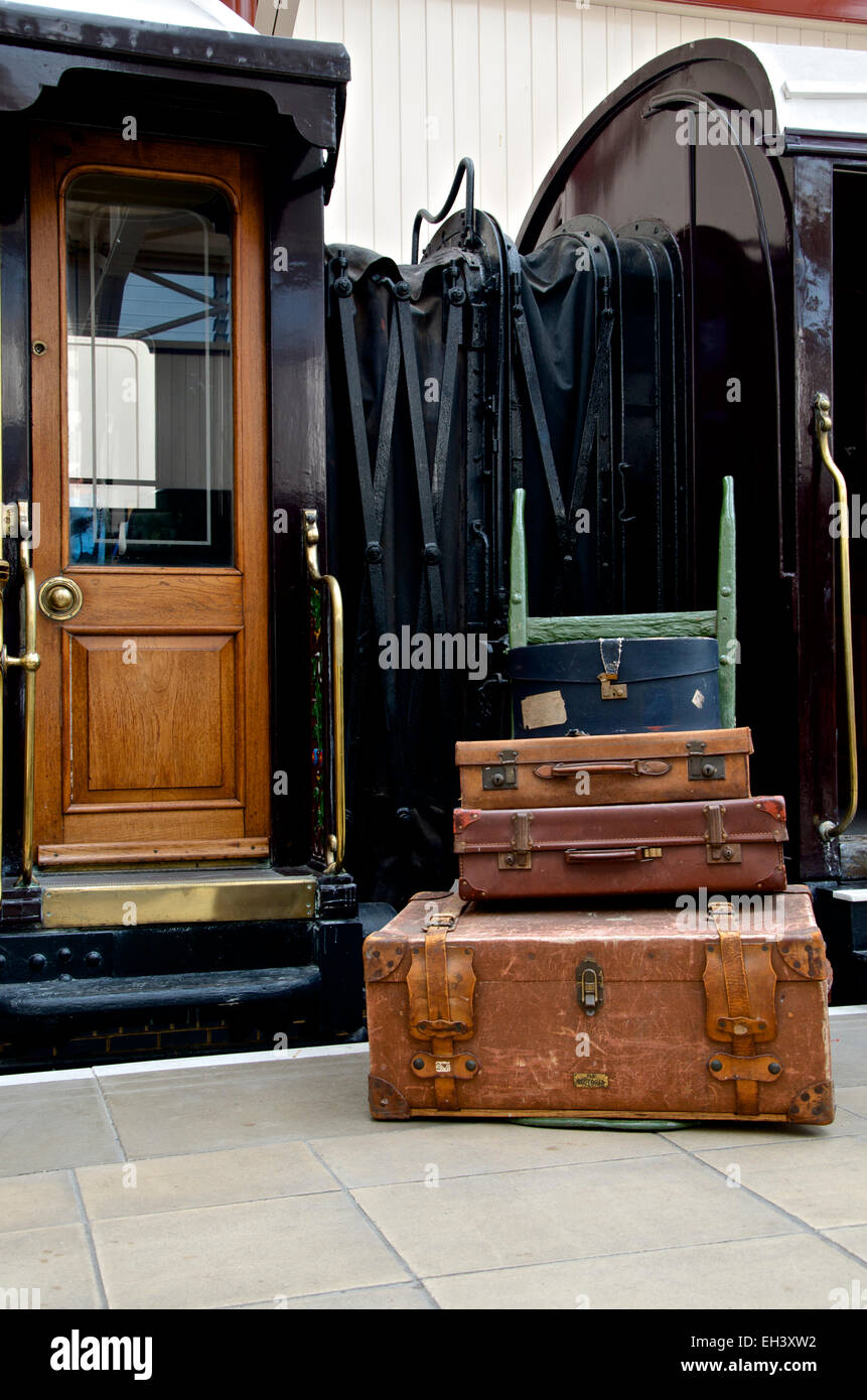 Luggage on a hand trolley along side a gilded LNWR First Class sleeping railway coach. Stock Photo