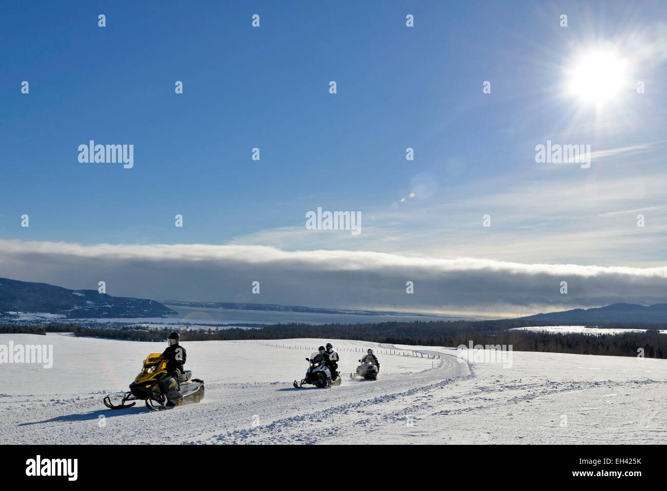 Canada, Quebec province, region of Charlevoix, Baie Saint Paul, snowmobiles in single file with the river background Saint Laurent Stock Photo