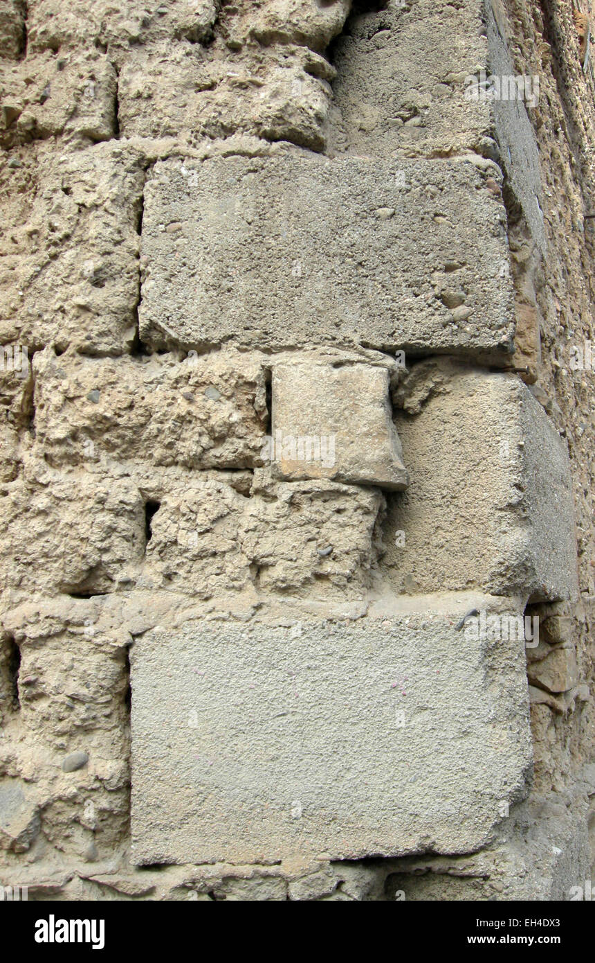 Particular of edge of wall of mud bricks with some little stones and straw and concrete bricks in edge Stock Photo