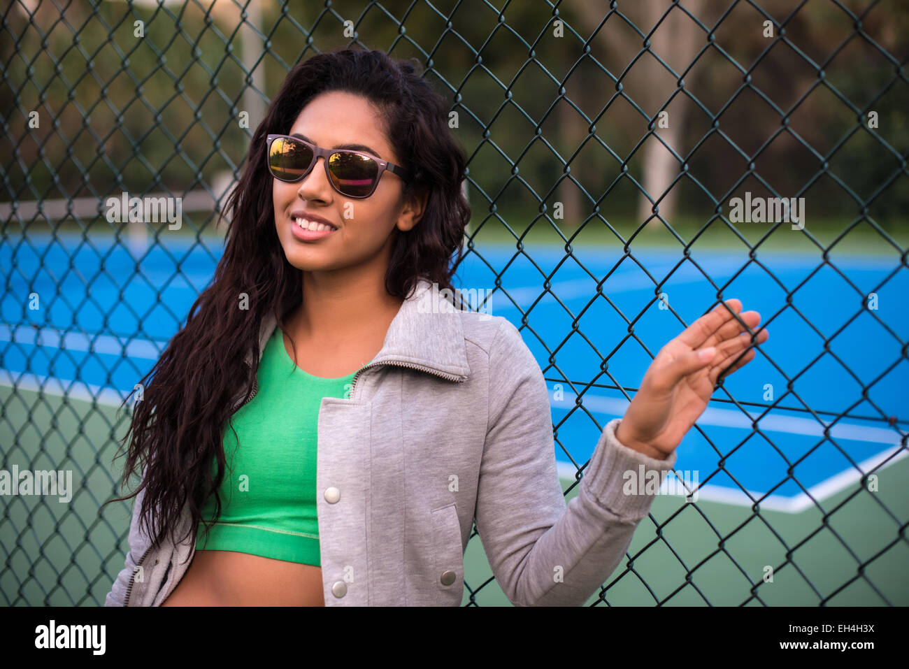 Woman wearing sunglasses over tennis court background Stock Photo