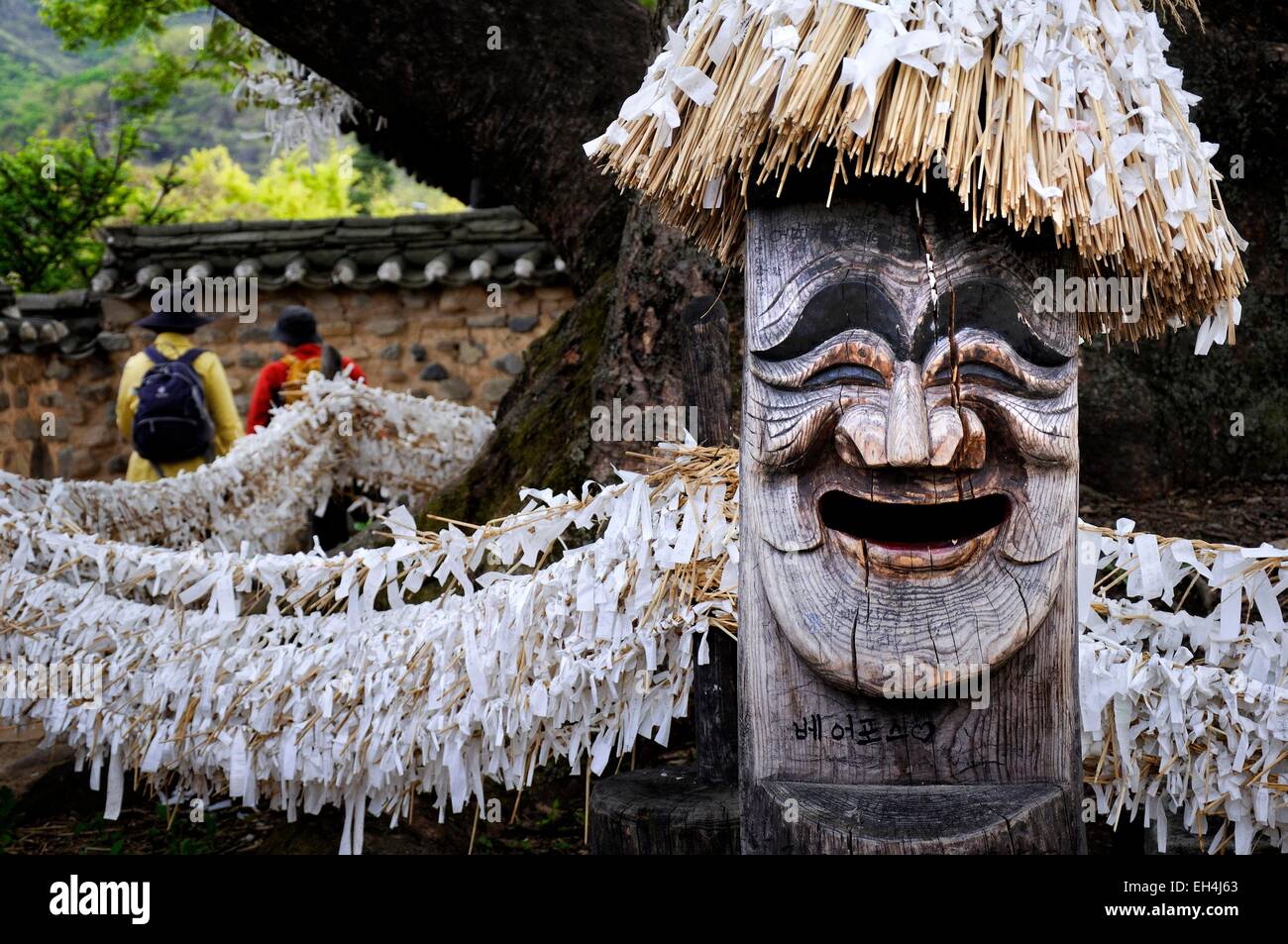 South Korea, North Gyeongsang Province (Gyeongsangbuk-do), Andong, Hahoe Folk Village listed as World Heritage by UNESCO, 600 years old Sinmok, a large and very old tree with a Jangseung, wooden totem pole with a laughing human face carved and a hat Stock Photo