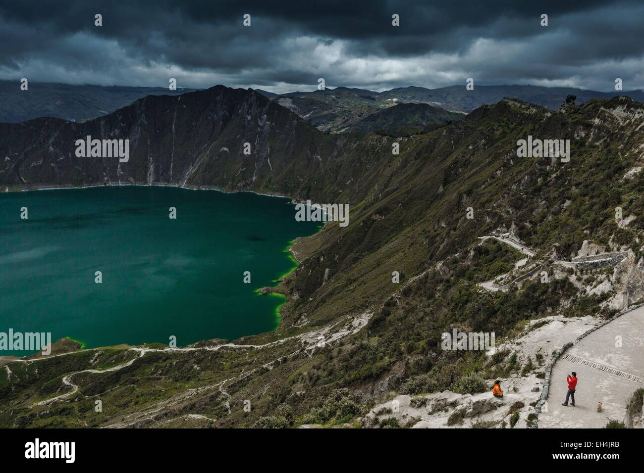 Ecuador, Cotopaxi, Quilotoa Crater Lake, panoramic view of tourists photographing over a lagoon in the crater of an extinct volcano, under a stormy sky Stock Photo
