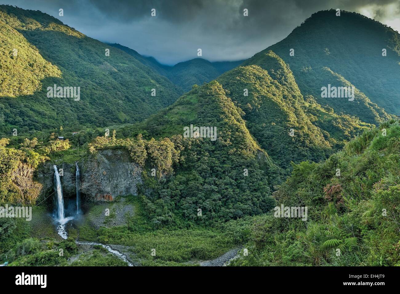 Ecuador, Tungurahua, Banos de Agua Santa, mountainous landscape with a waterfall in a tropical greenery caskets at sunset on a stormy sky Stock Photo