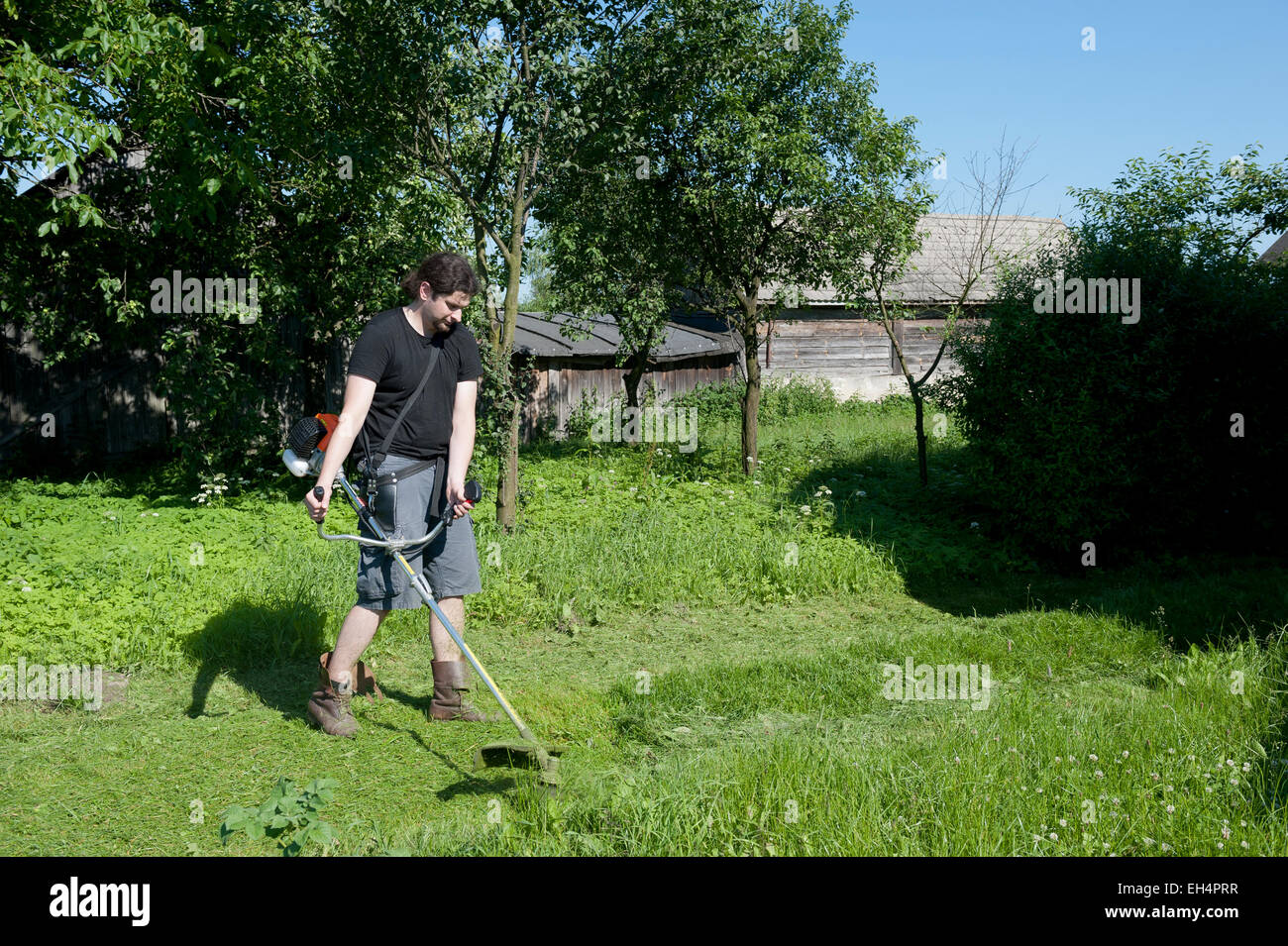 Man with a brushcutter working in a garden Stock Photo
