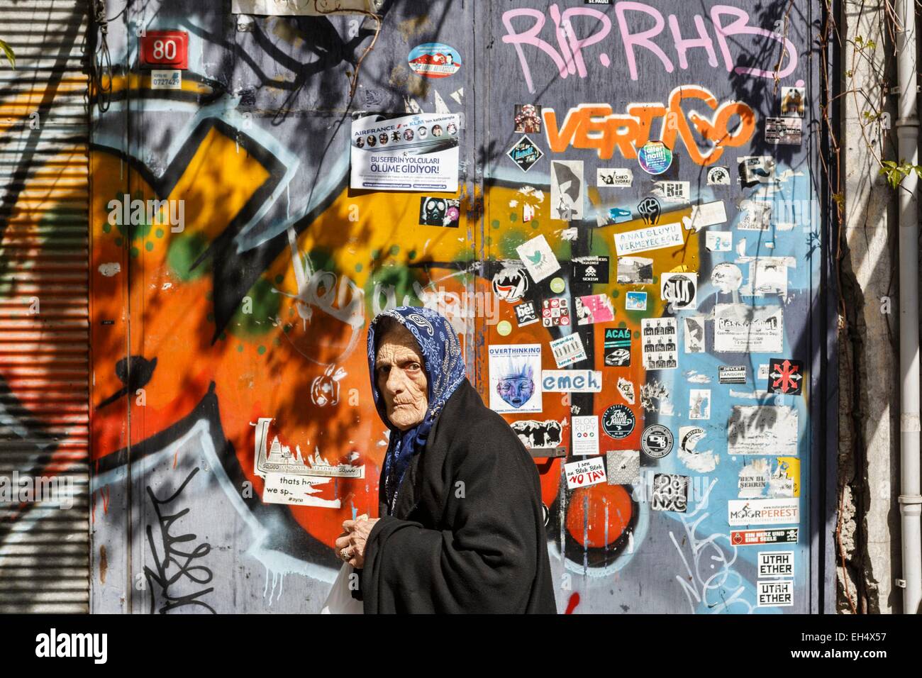 Turkey, Istanbul, Beyoglu, Galata, portrait of an old Turkish woman passing on the street on a graffiti background Stock Photo