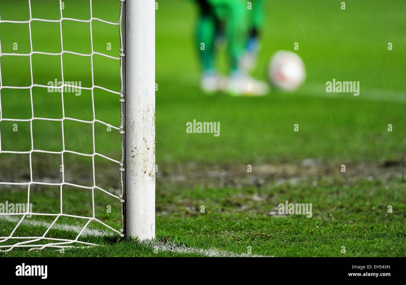 Soccer goal detail on rainy day with goalkeeper preparing for a goal kick in the background Stock Photo