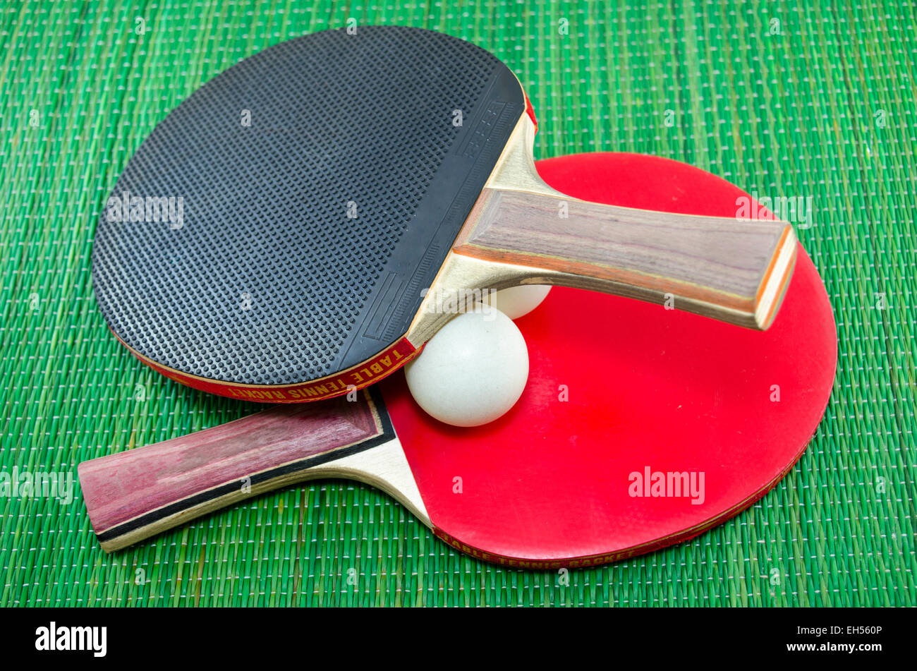 Two vintage table tennis rackets and two ping pong balls on a green background Stock Photo