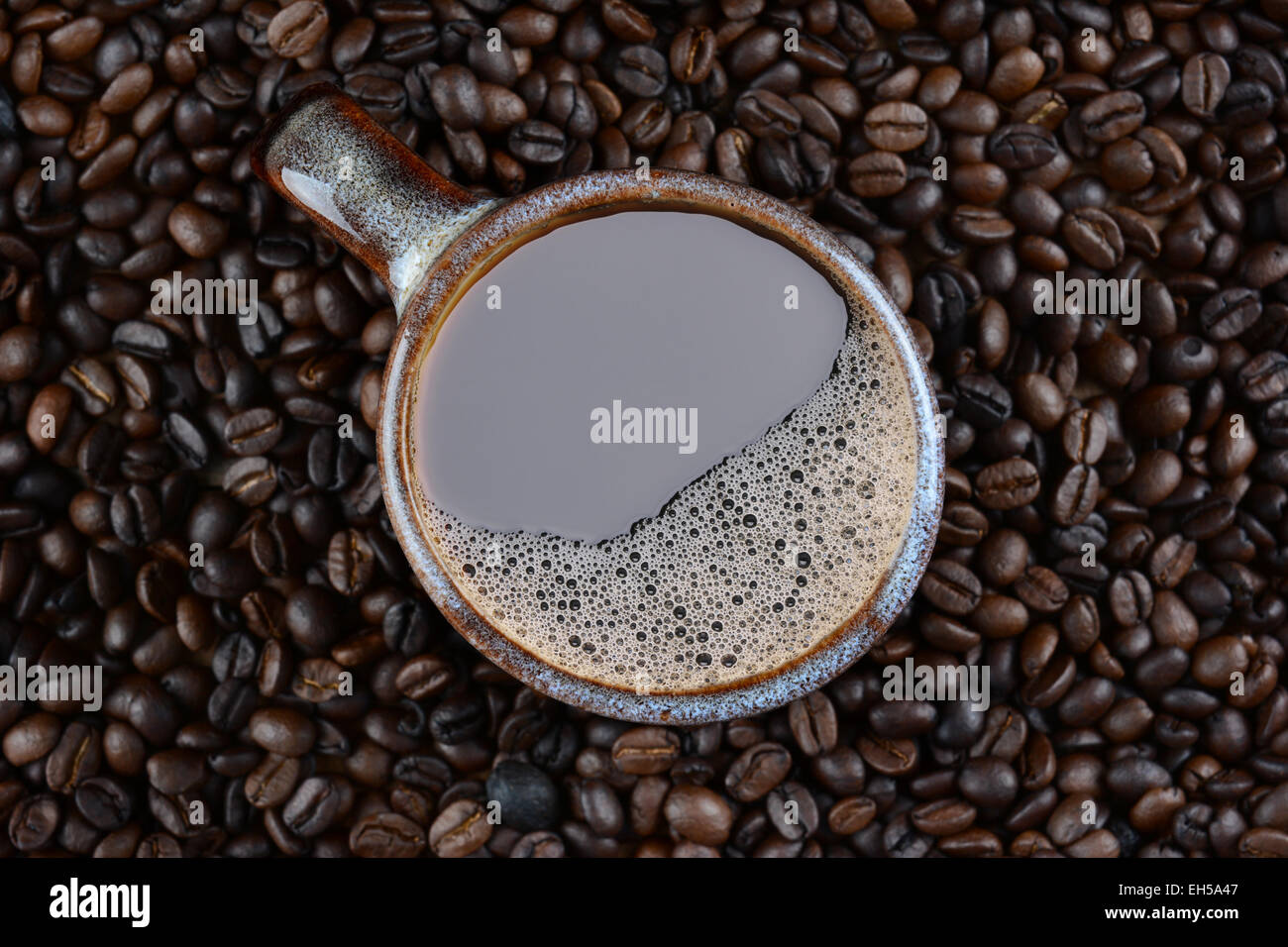 High angle shot of a coffee mug surrounded by fresh roasted beans. Stock Photo
