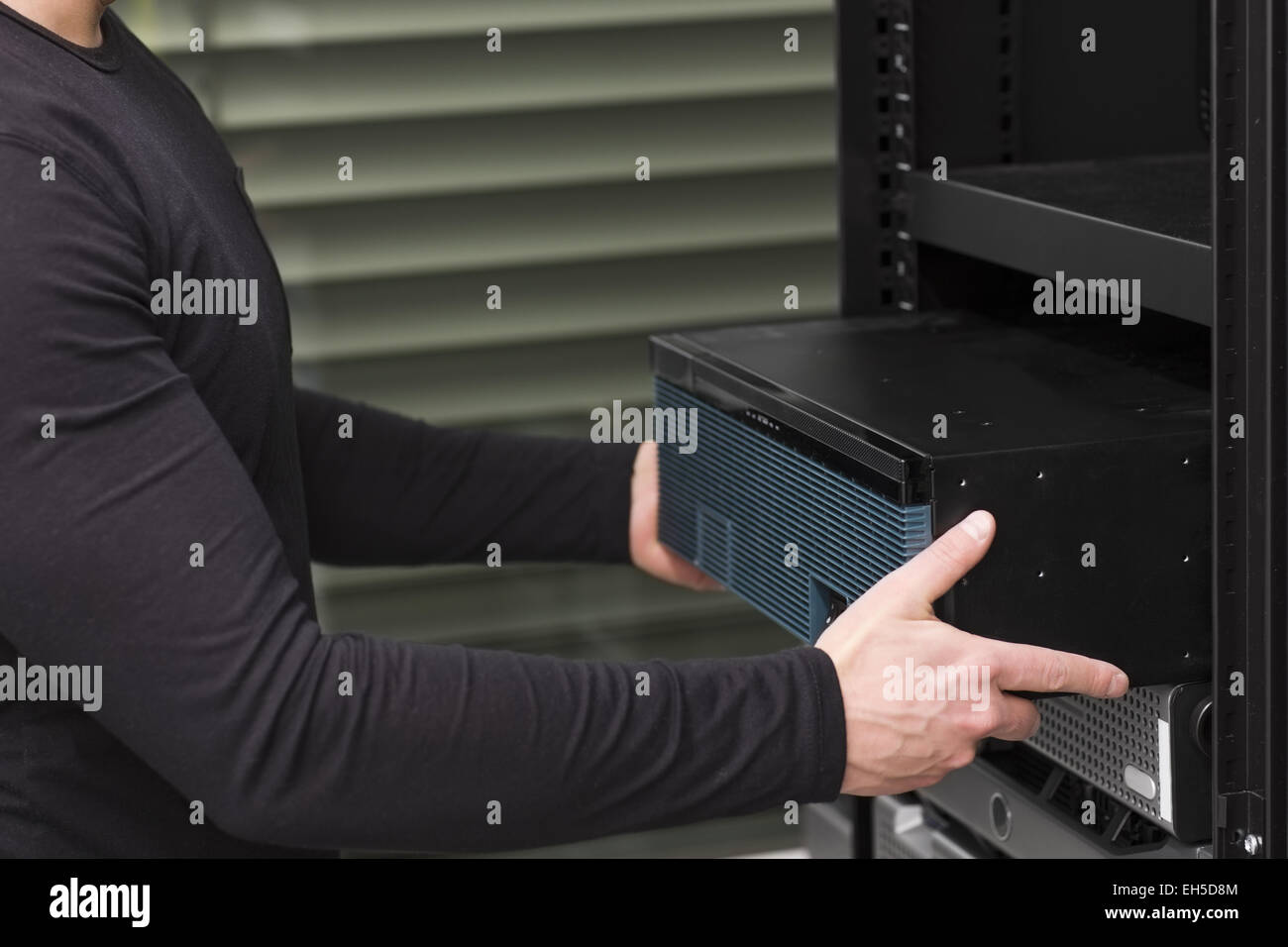 It engineer / consultant install / inserts a router / switch in a rack. Shot in a data center. Stock Photo