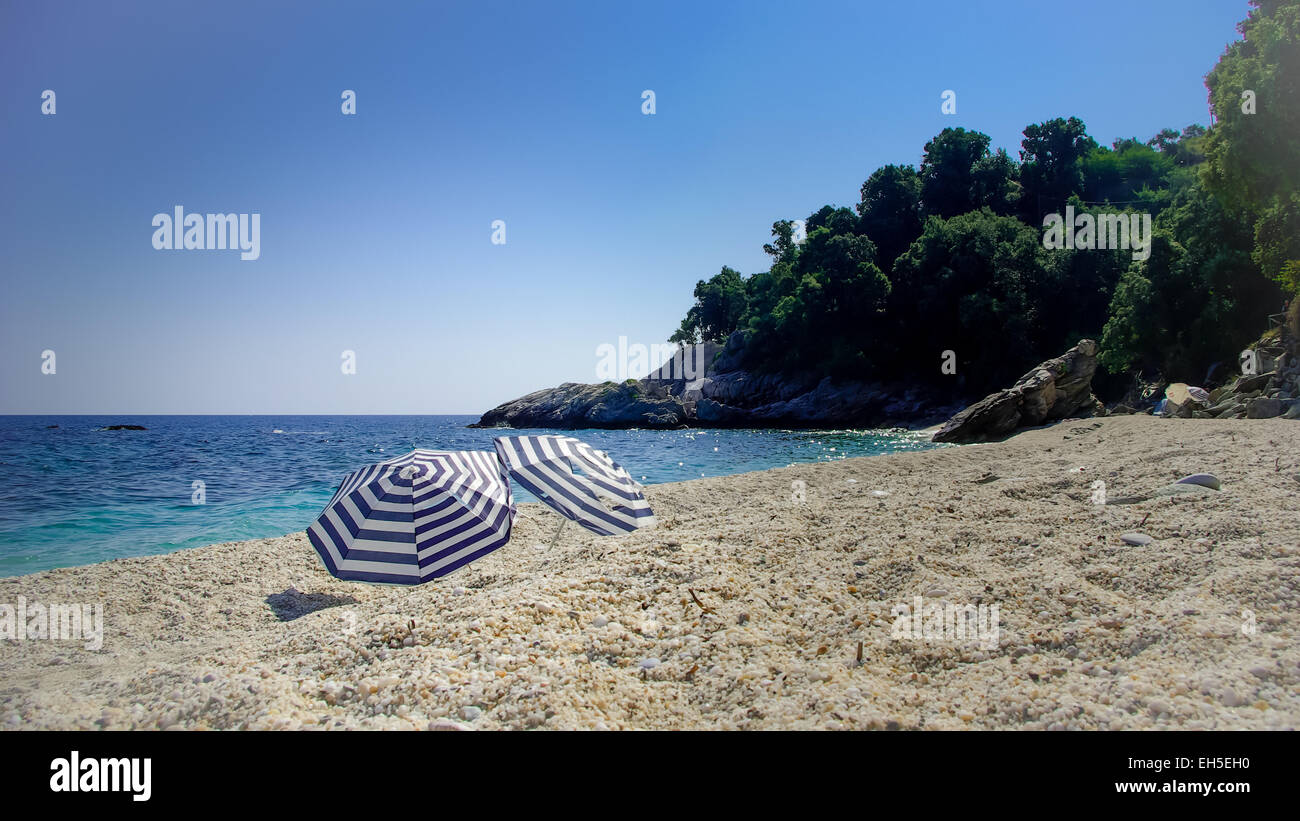 Two umbrellas on the beach.  Two parasols on a beautiful wild beach in Greece Stock Photo