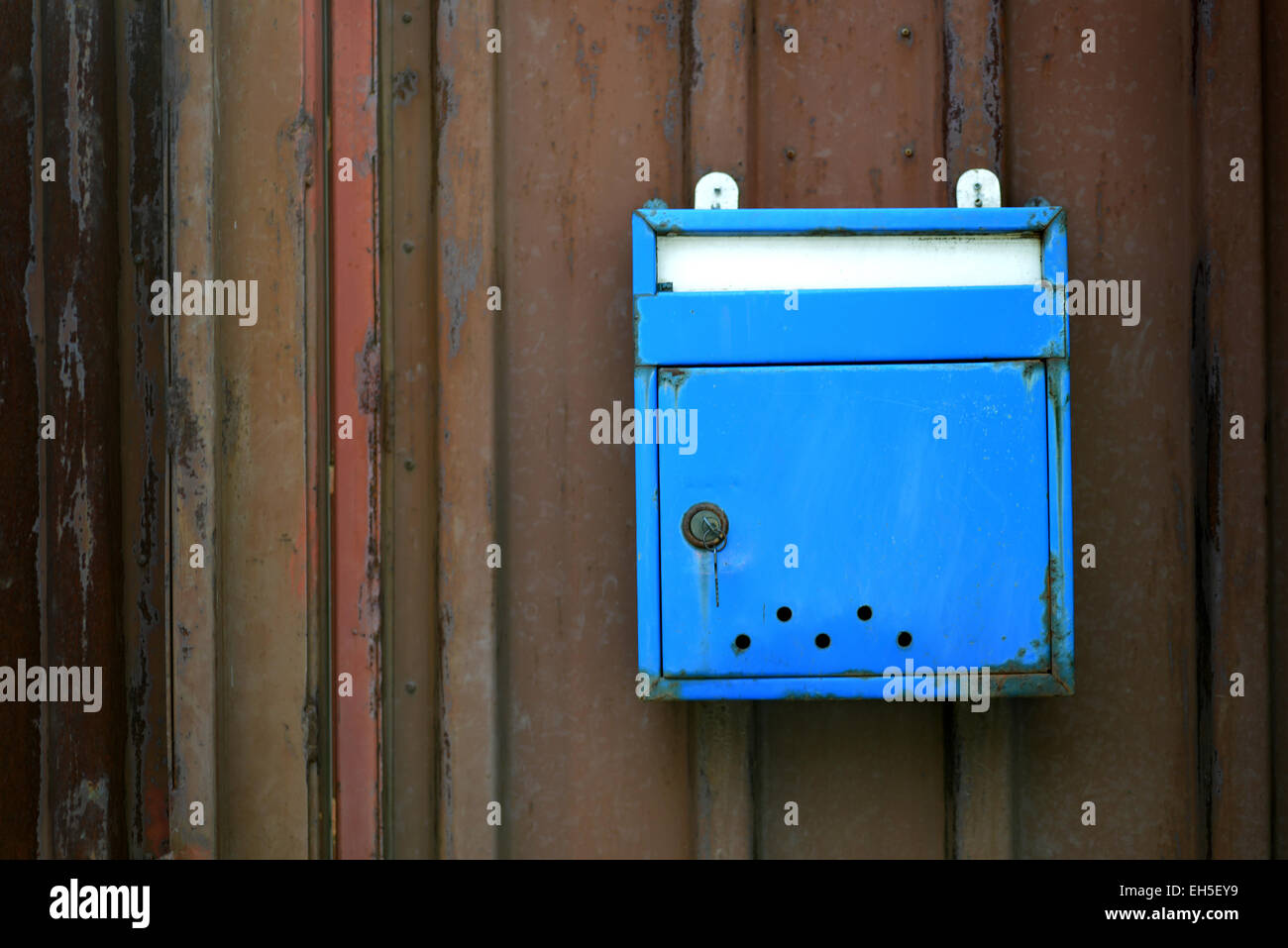 Old blue mailbox hanging in a fence board Stock Photo