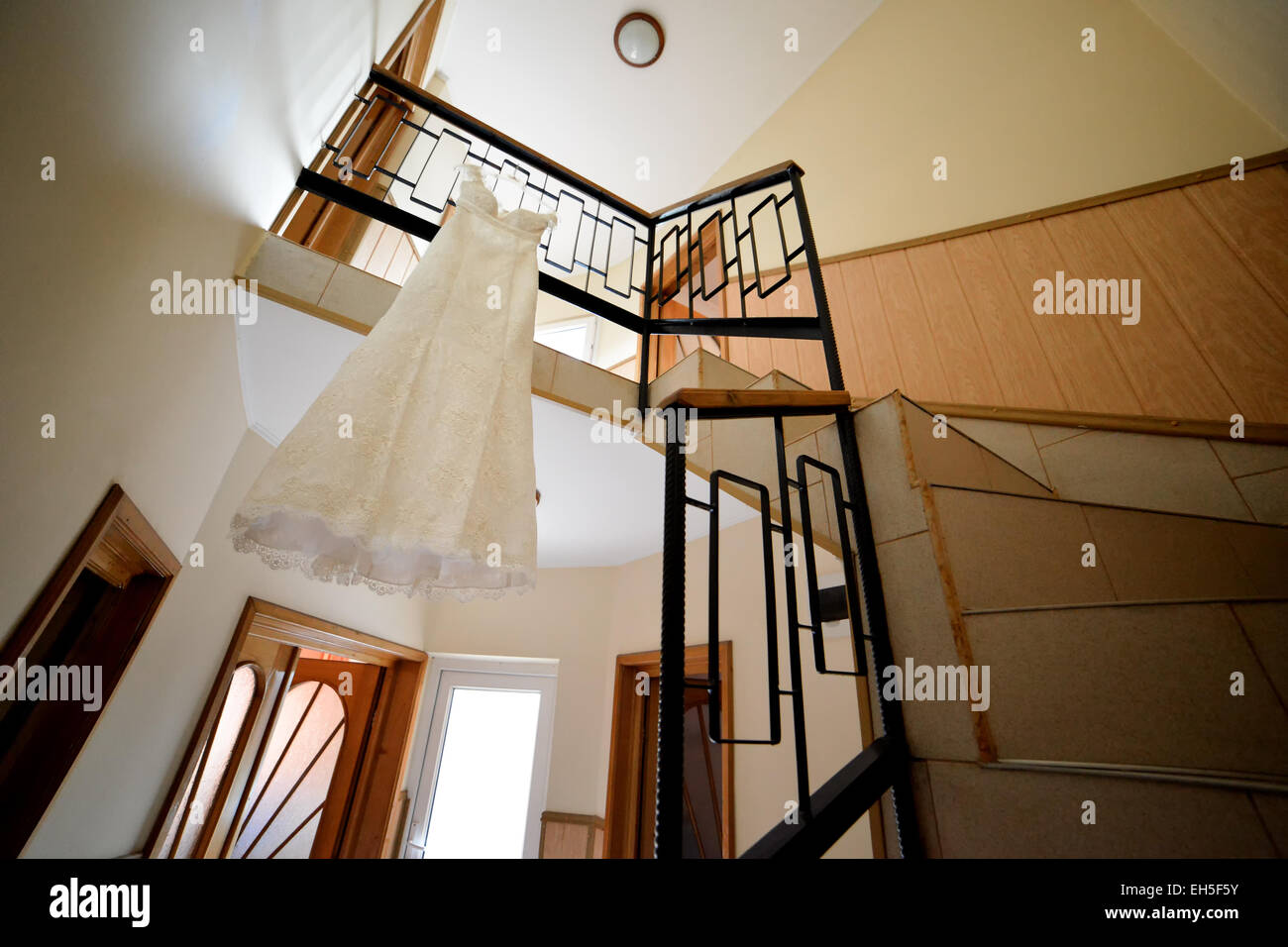 Cream wedding dress hanging from a railing in house Stock Photo