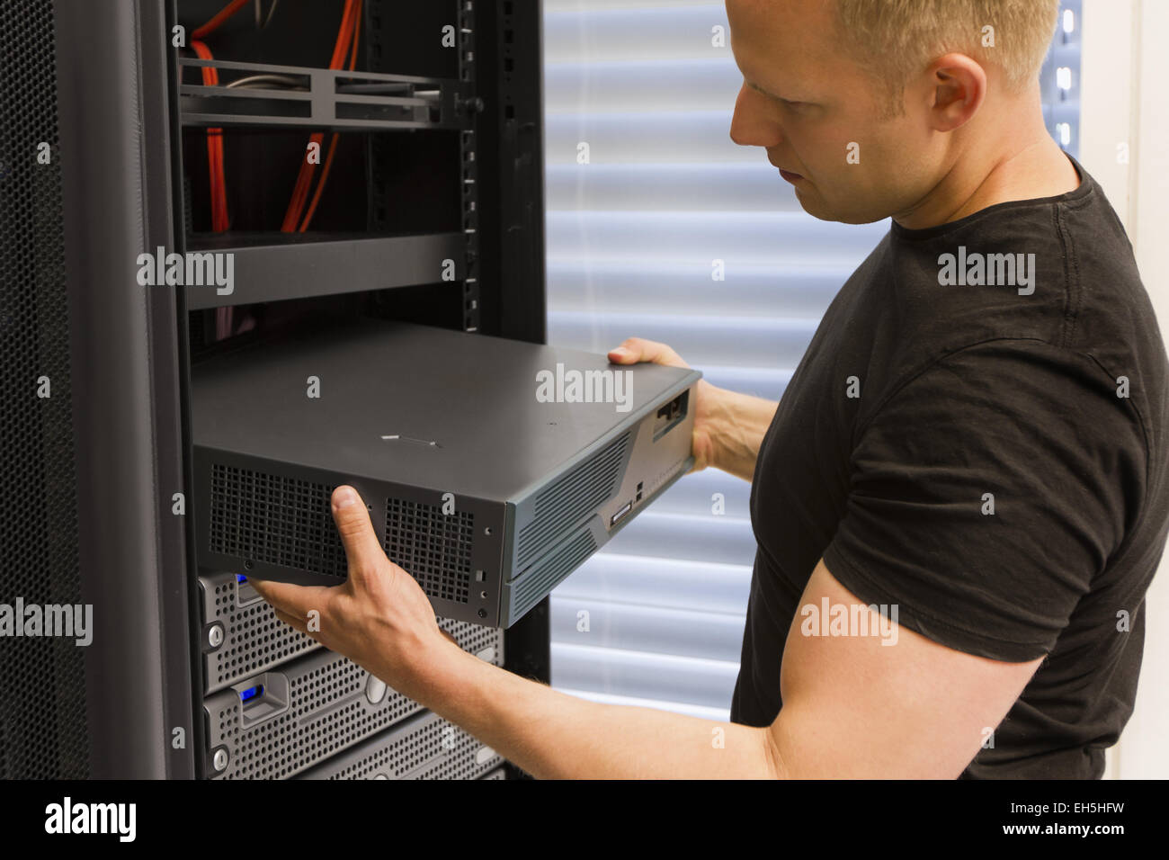 It engineer / consultant install / inserts a router / switch in a rack ...