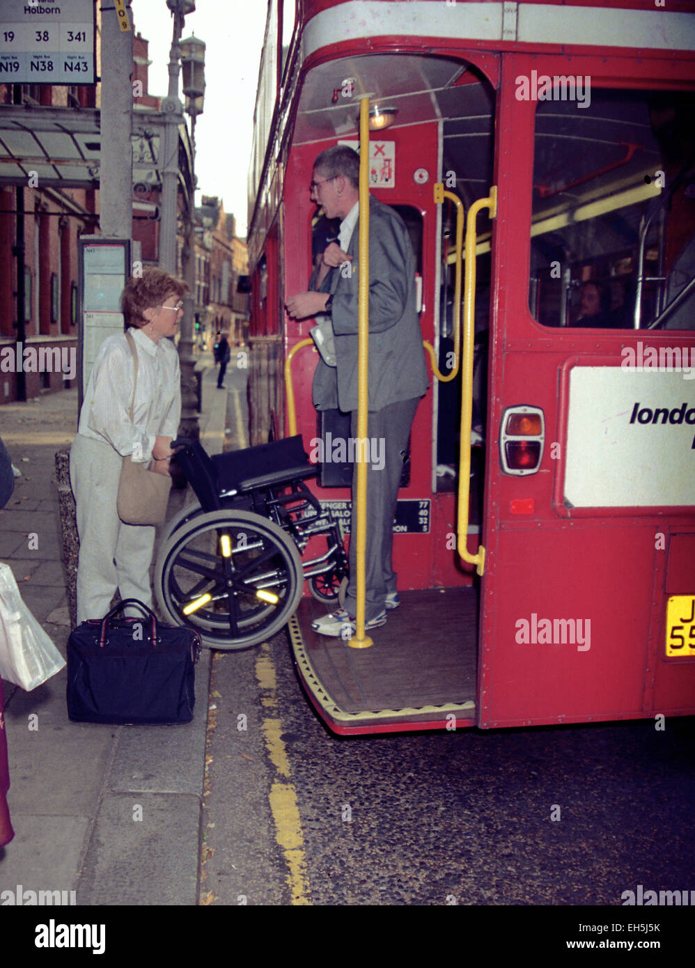 Lady with wheel chair tries to board London Routemaster buss, 2003 (credit image©Jack Ludlam) Stock Photo