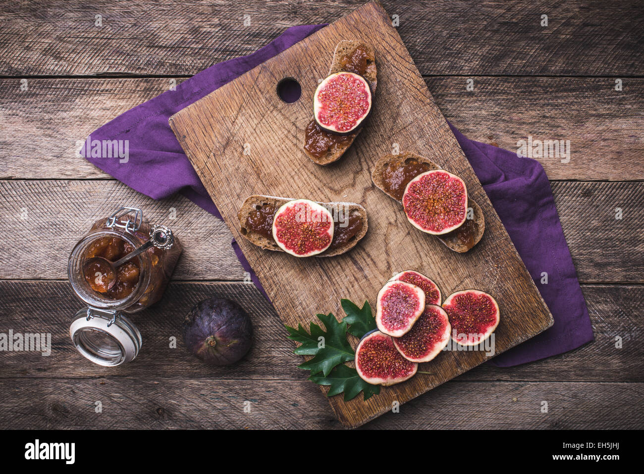 Sliced figs and bread with jam on choppingboard in rustic style. Autumn season food photo Stock Photo