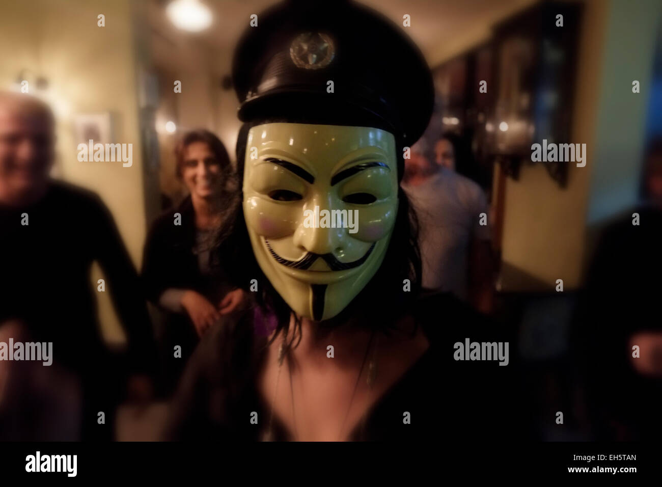 Woman wearing Guy Fawkes mask in a restaurant bar in West Jerusalem Israel. The Guy Fawkes mask is a well-known symbol for the online hacktivist group Anonymous used in anti-government and anti-establishment protests around the world. Stock Photo