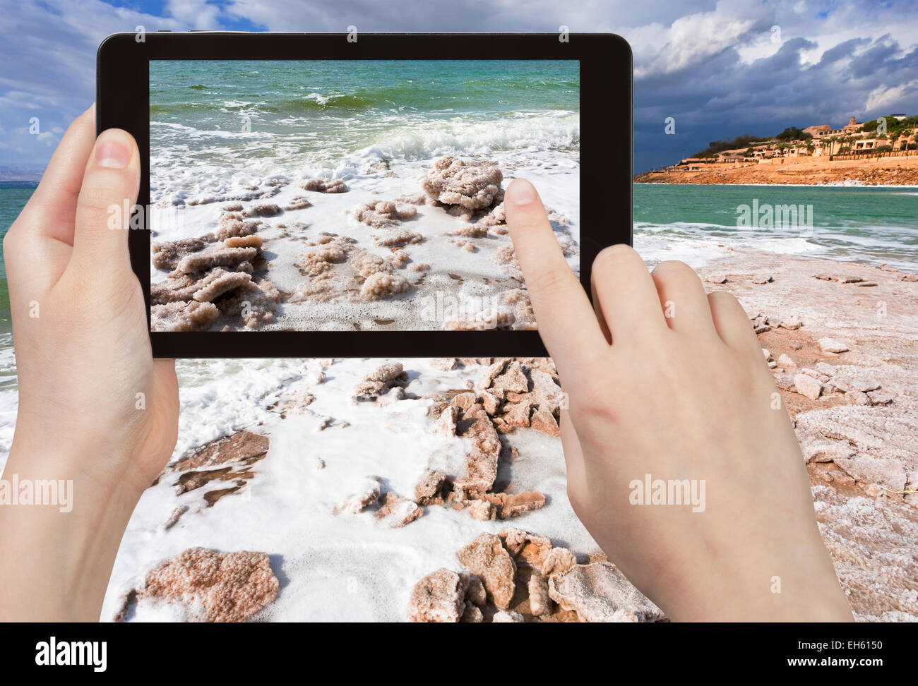 travel concept - tourist taking photo of crystal salt beach on Dead Sea coastline, Jordan on mobile gadget Stock Photo