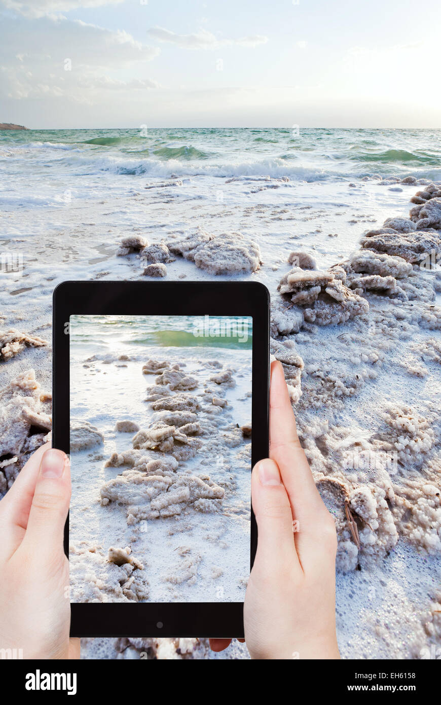 travel concept - tourist snapping photo of crystal salt on Dead Sea beach on mobile gadget, Jordan Stock Photo