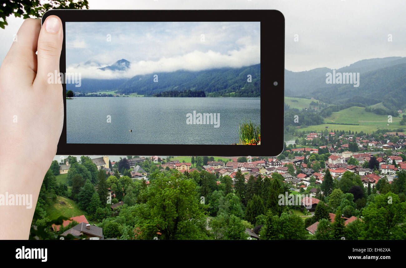 travel concept - tourist taking photo of Schliersee town - climatic health resort in Bavarian Alps on mobile gadget, Germany Stock Photo