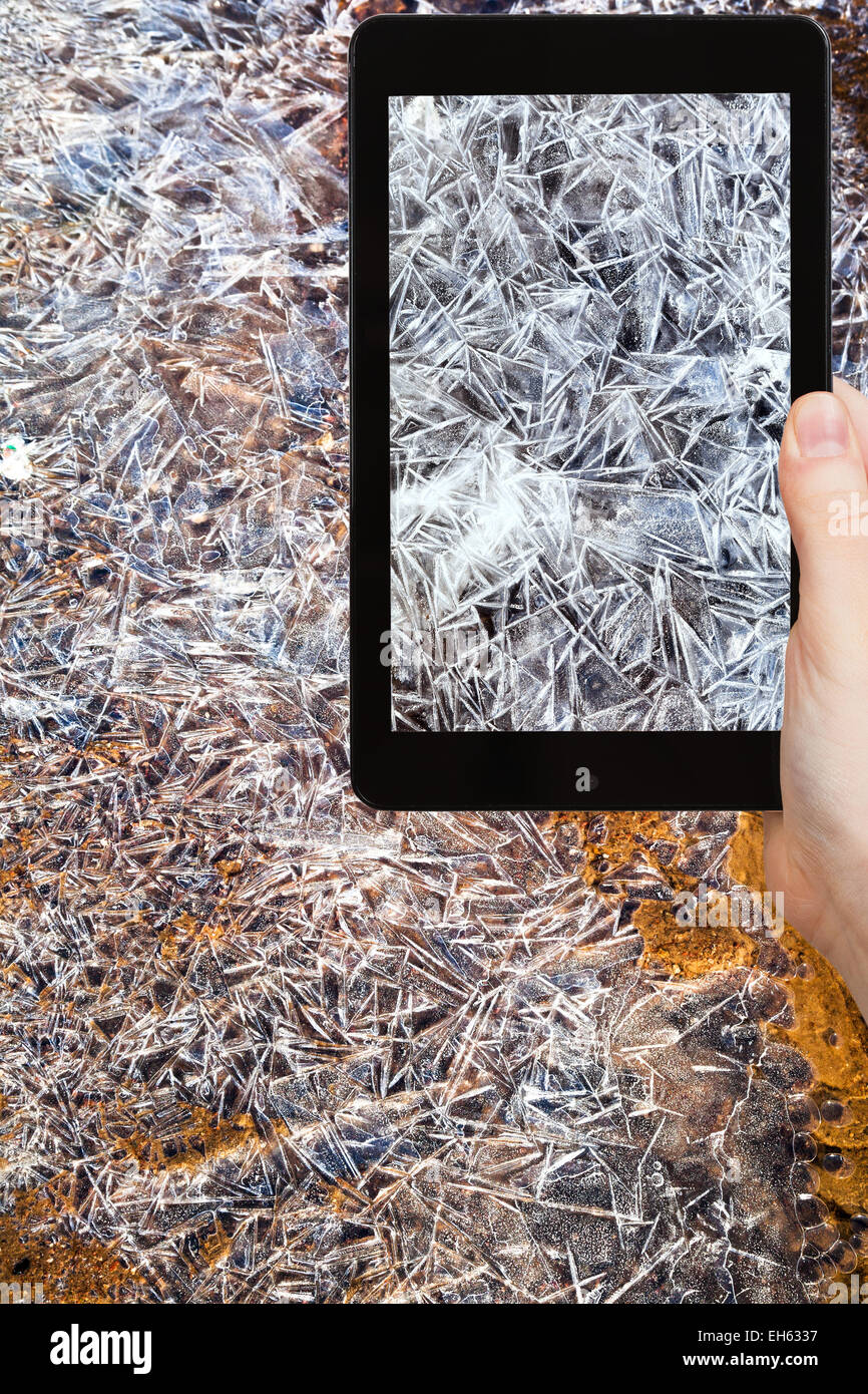 travel concept - tourist taking photo of ice crystal on frozen water on mobile gadget Stock Photo