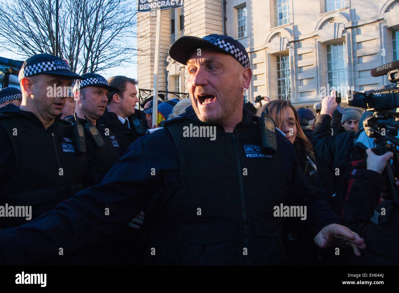 London, UK. 7th March, 2015. Following the Climate march through London, masked anarchists and environmental activists clash with police following a breakaway protest at Shell House. PICTURED: A TSG police officer shouts orders as anti-fracking activists and anarchist block the departure of a police van containing one of their colleagues. Credit:  Paul Davey/Alamy Live News Stock Photo