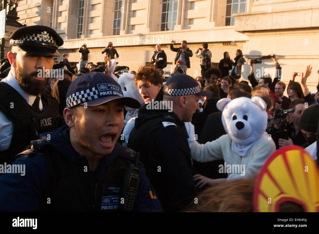 London, UK. 7th March, 2015. Following the Climate march through London, masked anarchists and environmental activists clash with police following a breakaway protest at Shell House. PICTURED: A man dressed in a polar bear suitlooks on as a TSG officer shouts at activists blocking the path of a police van containing a colleague of the protesters arrested earlier. Credit:  Paul Davey/Alamy Live News Stock Photo