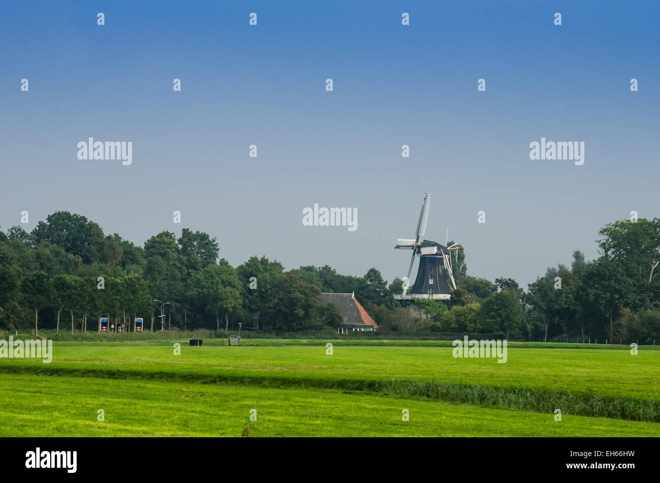 A windmill in Northern Europe behind grassy farmland Stock Photo