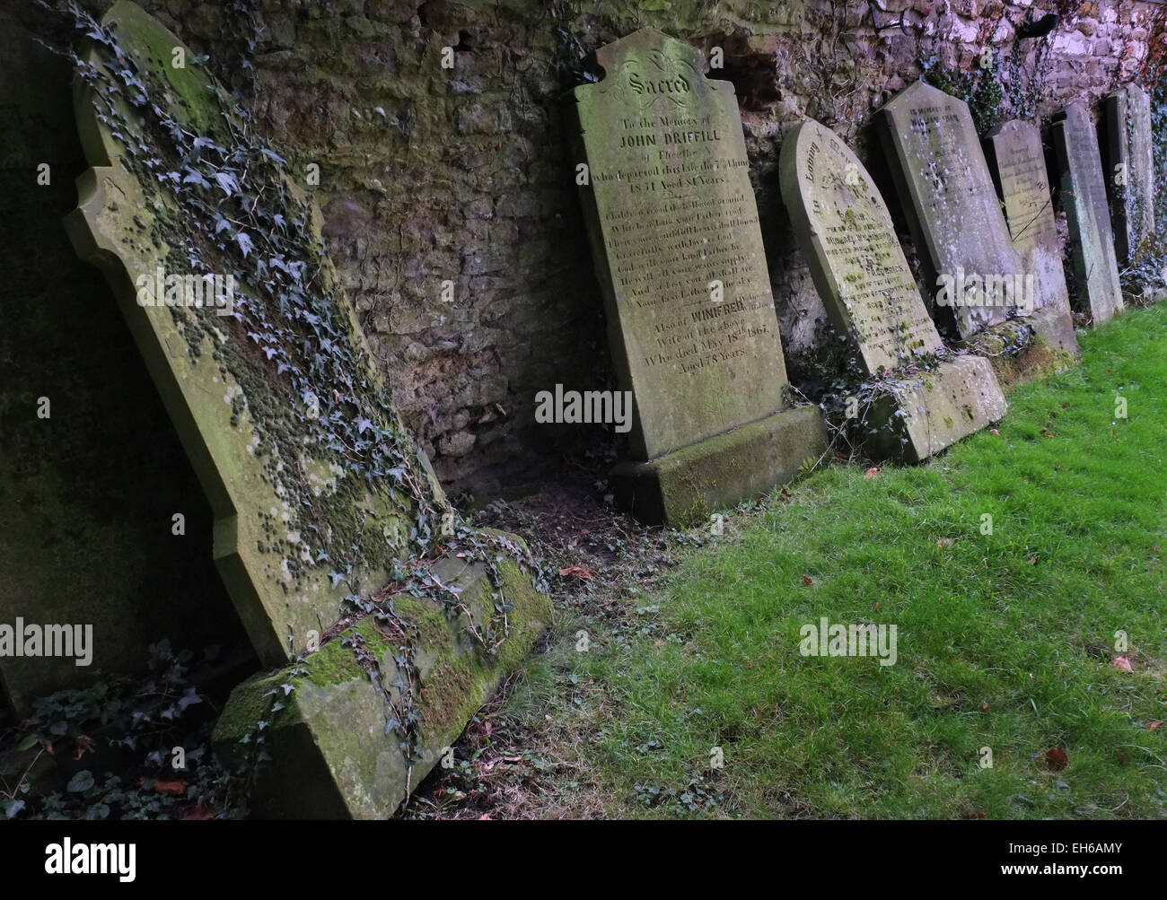 Old grave stones leaning on wall. Stock Photo