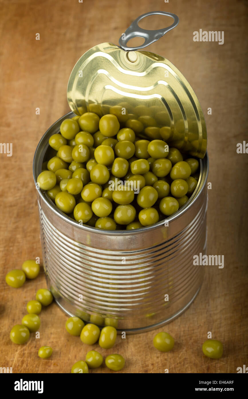 Opened tin with green peas over wood background Stock Photo