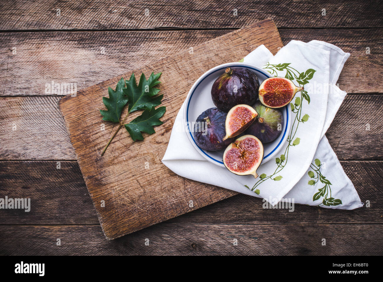 Figs in flat dish on choppingboard and napkin in rustic style. Autumn season food photo Stock Photo