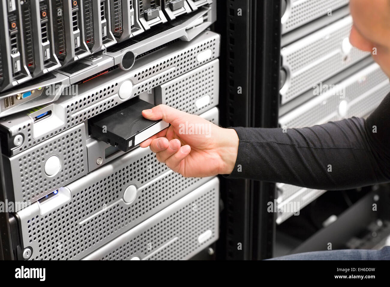 It engineer or consultant working with backup server in racks. Shot in data center. Stock Photo